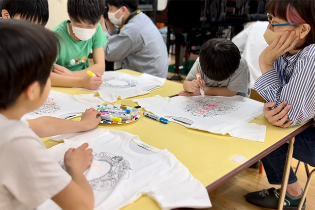Los niños dibujan en la camiseta con marcadores.