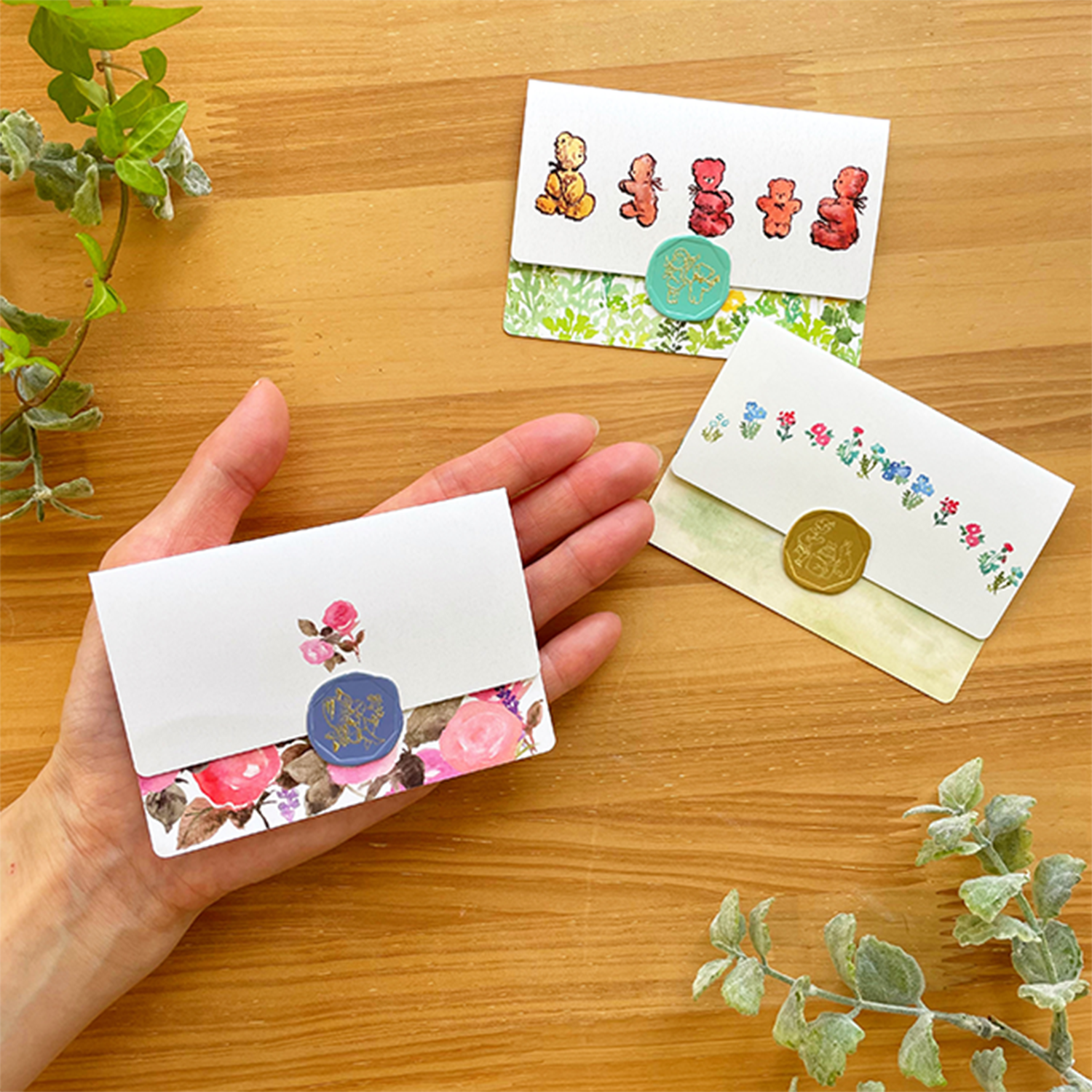 A folded message card with a sticker on a hand. Other 2 message cards on wooden table.