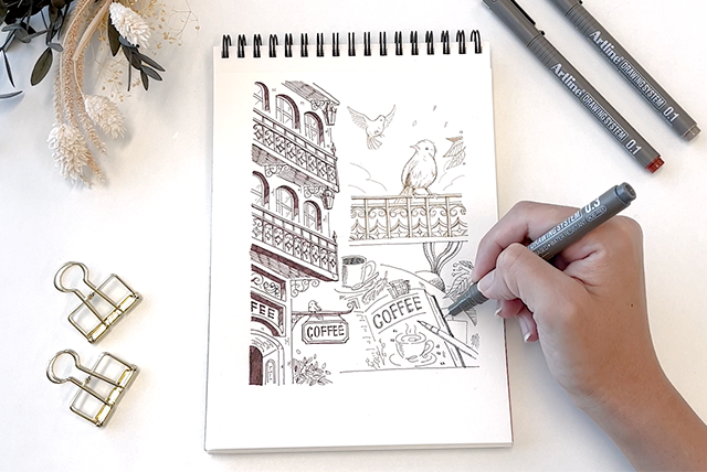 A hand drawing illustrations on a sketch book  with Artline DRAWING SYSTEM pen