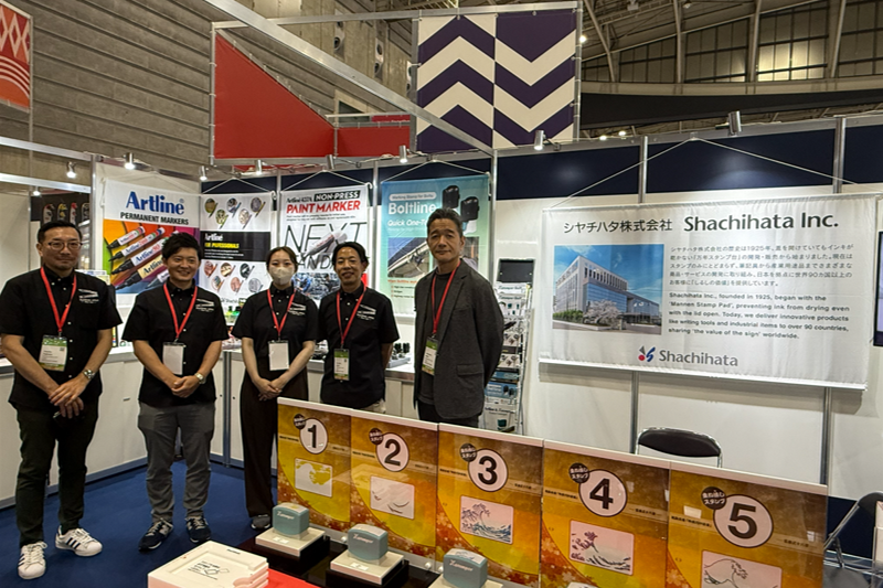 Shachihata staff members standing in front of the exhibition booth