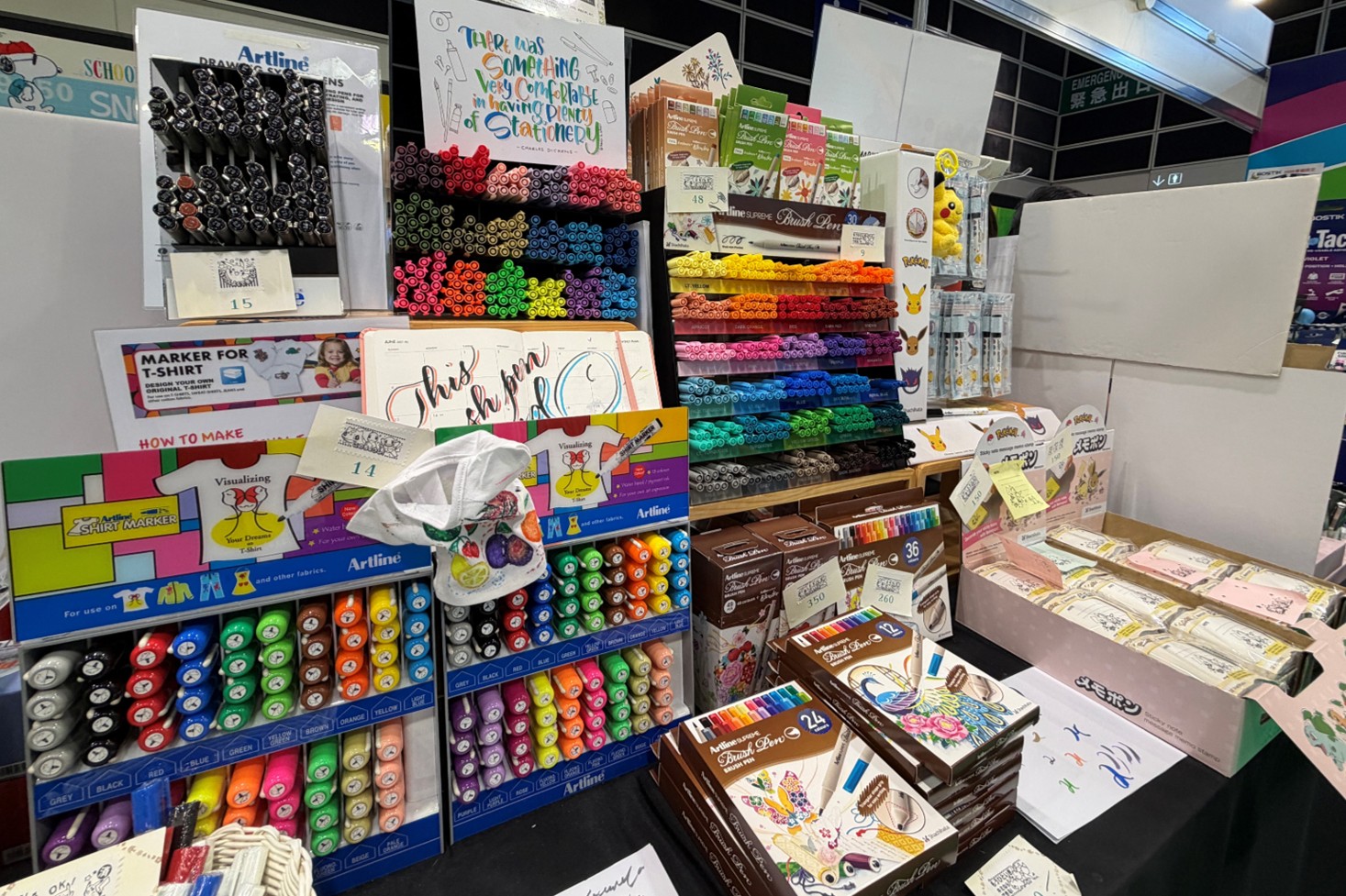 The display mainly features the Artline SUPREME Blush Pen and Artline SHIRT MARKER.