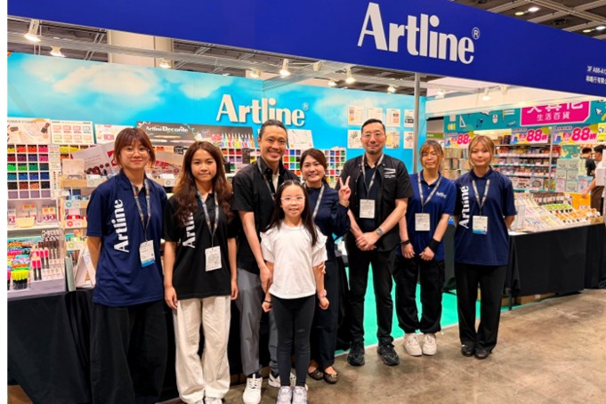 They’re taking a group photo in front of the Artline booth.