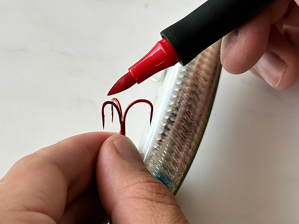 painting metal fishing hook with red ink marker